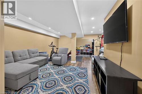 Recessed lighting illuminates the space, featuring wood-finish flooring and a built-in media console - 149 Kinsman Drive, Binbrook, ON 