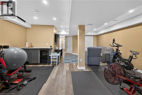 Finished lower level featuring recessed lighting, wood-finish flooring, a built-in wet bar with sink, and integrated beverage refrigeration - 149 Kinsman Drive, Binbrook, ON 