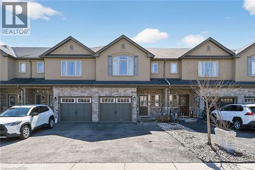 Townhome exterior featuring stone and stucco finishes, multiple dormers, and individual garages - 149 Kinsman Drive, Binbrook, ON 