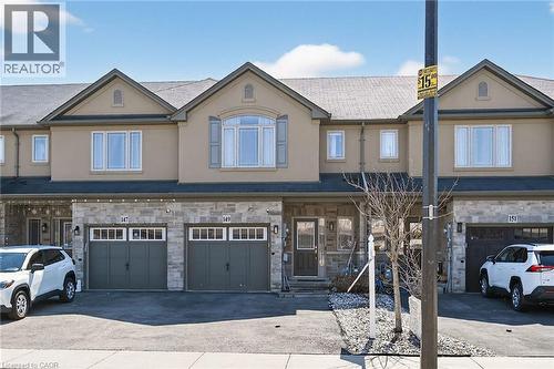 Townhome exterior featuring a stone and stucco facade, an attached garage, and a paved driveway - 149 Kinsman Drive, Binbrook, ON 