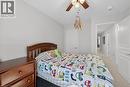 Light gray painted walls define this bedroom with a wood-finish bed frame, wood-finish ceiling fan with integrated lighting, and light-colored carpeting - 149 Kinsman Drive, Binbrook, ON 