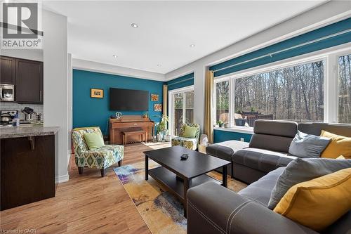 Bright living area featuring large windows, wood-finish flooring, recessed lighting, a sliding glass door, and an open concept layout with a kitchen pass-through - 149 Kinsman Drive, Binbrook, ON 