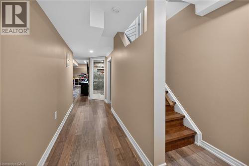 Lower-level hallway featuring wood-finish flooring, recessed lighting, and a partial staircase with wood treads and white risers - 149 Kinsman Drive, Binbrook, ON 
