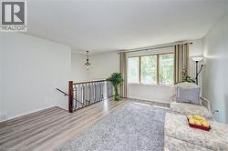 Bright room featuring wood-finish flooring, a contemporary black metal and wood railing, and a multi-pane window - 