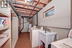 Laundry area featuring a utility sink, exposed ceiling beams, and a high-set window - 