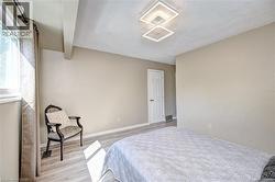 Room featuring neutral wall tones, wood-finish flooring, a white trim door, a modern geometric ceiling light fixture, and a window with white casing - 