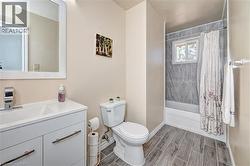 Bathroom featuring wood-finish flooring and a white vanity with a rectangular sink - 