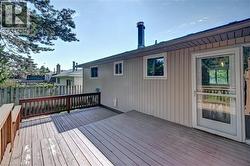 Spacious wooden deck featuring a perimeter railing, light-colored vertical siding, and a glass-paneled exterior door - 