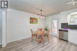 Dining area featuring wood-finish flooring and a contemporary linear pendant light fixture - 