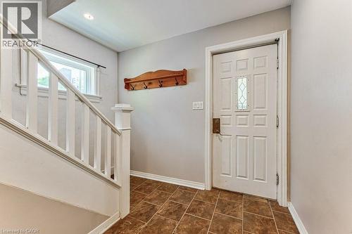 Entryway featuring a paneled door with decorative glass inserts, brown tiled flooring, and a white painted staircase with wood handrails - 84 Franklin Street S, Kitchener, ON - Indoor Photo Showing Other Room