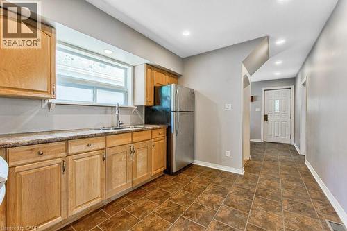 Kitchen featuring wood-finish cabinetry, light-toned countertops, and a stainless steel refrigerator - 84 Franklin Street S, Kitchener, ON - Indoor Photo Showing Kitchen With Double Sink