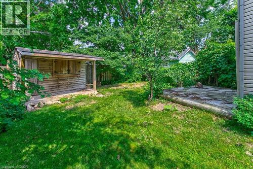 Grassed outdoor area featuring a wooden shed structure, mature trees, and a ground-level patio space - 84 Franklin Street S, Kitchener, ON - Outdoor
