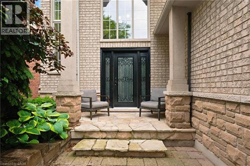 Expansive front entrance featuring door with decorative ironwork, brick and stone facade, and a stone slab patio - 207 Valridge Drive, Ancaster, ON - Outdoor