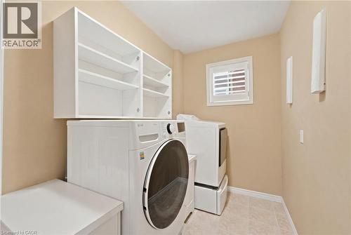 Laundry room featuring white cabinetry, a window with california shutters, tile flooring, and light-toned walls - 207 Valridge Drive, Ancaster, ON - Indoor Photo Showing Laundry Room