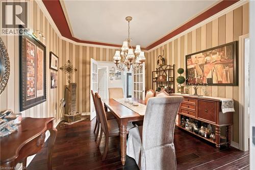 Formal dining room featuring french doors, rich wood-finish flooring, striped wall paint, and a decorative chandelier - 207 Valridge Drive, Ancaster, ON - Indoor Photo Showing Dining Room