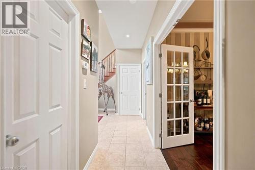 Hallway with tile flooring, leading to a staircase with wood railing - 207 Valridge Drive, Ancaster, ON - Indoor Photo Showing Other Room