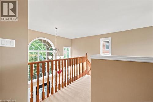 Upper landing open to entrance foyer featuring wood balusters, an arched window, and a decorative pendant light fixture - 207 Valridge Drive, Ancaster, ON - Indoor Photo Showing Other Room