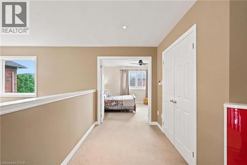 Carpeted hallway featuring a window with white trim, recessed lighting, and a double-door leading to the primary bedroom - 207 Valridge Drive, Ancaster, ON - Indoor