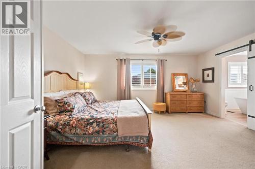Spacious primary bedroom featuring neutral carpeting, a ceiling fan with integrated lighting, and a window with california shutters - 207 Valridge Drive, Ancaster, ON - Indoor Photo Showing Bedroom