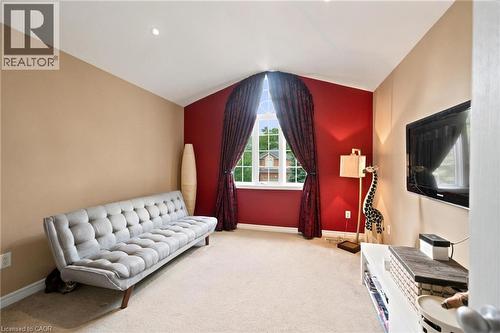 Bedroom featuring neutral wall colours with a red accent wall, cathedral-style ceilings, arched window, and carpet flooring - 207 Valridge Drive, Ancaster, ON - Indoor