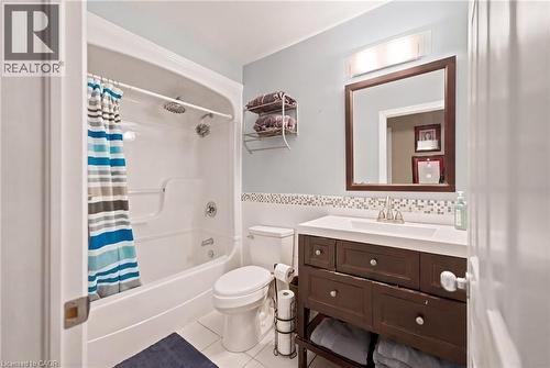 Bathroom featuring a white tub/shower combination, white tile flooring, a dark wood-finish vanity with a white countertop, and a mosaic tile backsplash - 207 Valridge Drive, Ancaster, ON - Indoor Photo Showing Bathroom