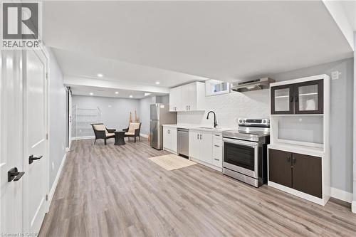 Open-concept space featuring wood-finish flooring, recessed lighting, and a modern kitchen with stainless steel appliances - 207 Valridge Drive, Ancaster, ON - Indoor Photo Showing Other Room