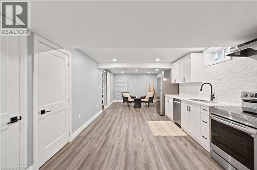 Open-concept living space featuring a modern kitchen with white cabinetry, stainless steel appliances, and a subway tile backsplash - 207 Valridge Drive, Ancaster, ON - Indoor Photo Showing Kitchen