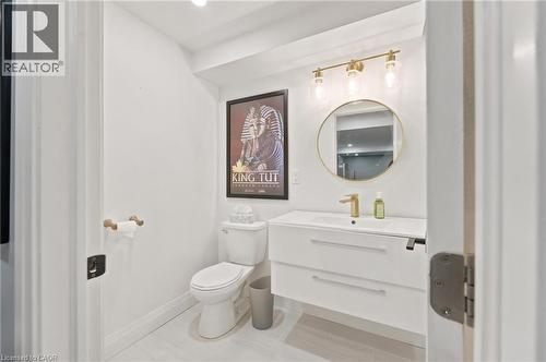 Modern bathroom featuring a floating white vanity with integrated sink, gold-finish faucet, and a circular frameless mirror - 207 Valridge Drive, Ancaster, ON - Indoor Photo Showing Bathroom