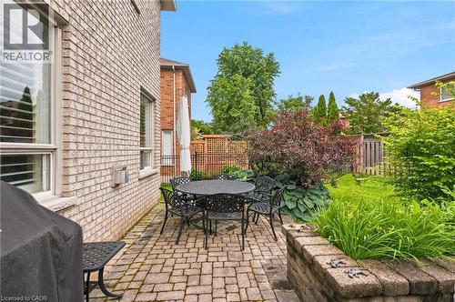 Brick paver patio with a stone planter and dark metal fencing - 207 Valridge Drive, Ancaster, ON - Outdoor