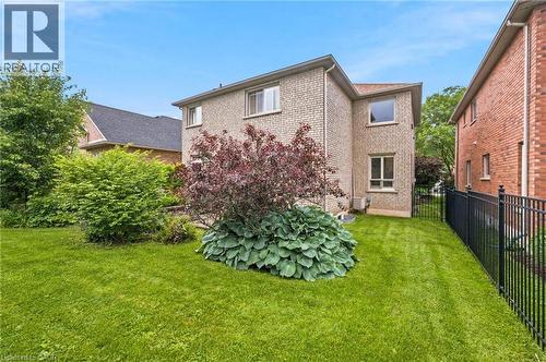 Expansive backyard featuring a manicured lawn, established landscaping, and a dark metal fence - 207 Valridge Drive, Ancaster, ON - Outdoor With Exterior