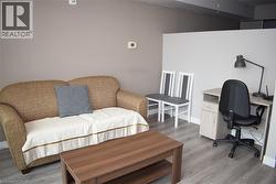 Living area featuring wood-finish flooring, a neutral wall color, and a partial wall separation - 