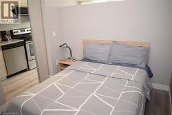 Compact living space featuring wood-finish flooring and a light-toned wood headboard - 