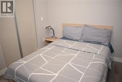 Bedroom featuring sliding closet doors, a light wood headboard, and wood-finish flooring - 