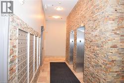 Entryway featuring two stainless steel elevators, natural stone tile flooring, and decorative stacked stone wall accents - 