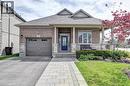 Brick and stone facade bungalow featuring a covered front porch with columns, an asphalt driveway, a paver stone walkway, and a single-car garage with an overhead door - 219 Falconridge Drive, Kitchener, ON  - Outdoor With Facade 
