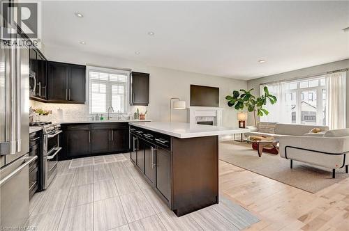 Open-concept living space featuring a modern kitchen with dark wood cabinetry, stainless steel appliances, and a central island with a light-colored countertop - 219 Falconridge Drive, Kitchener, ON - Indoor Photo Showing Kitchen