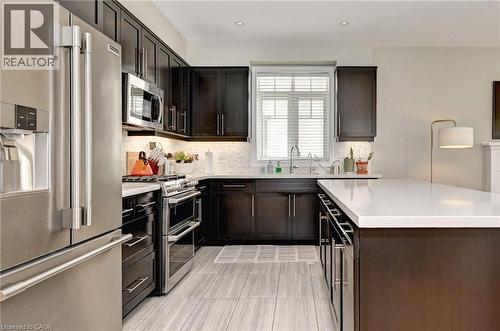 Gourmet kitchen featuring dark wood cabinetry, stainless steel appliances, white countertops, and a white tile backsplash - 219 Falconridge Drive, Kitchener, ON - Indoor Photo Showing Kitchen With Upgraded Kitchen