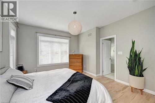 Bedroom featuring light wood-finish flooring, two large windows with blinds, a ceiling-mounted light fixture, and a white interior door - 219 Falconridge Drive, Kitchener, ON - Indoor Photo Showing Bedroom