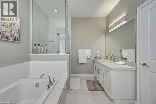 Contemporary bathroom featuring a freestanding tub, glass-enclosed shower, white subway tile accents, and a dual-sink vanity with a large mirror - 219 Falconridge Drive, Kitchener, ON - Indoor Photo Showing Bathroom