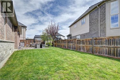 Expansive rear yard featuring a large lawn, mature privacy fencing, and a stone patio - 219 Falconridge Drive, Kitchener, ON - Outdoor