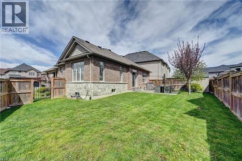 Expansive backyard featuring a manicured lawn, full perimeter wood fencing, and a concrete patio - 219 Falconridge Drive, Kitchener, ON - Outdoor With Deck Patio Veranda
