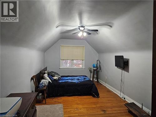 Room featuring sloped ceilings, a window with blinds, wood-finish flooring, a ceiling fan, and light gray wall paint - 75 Barons Avenue S, Hamilton, ON - Indoor Photo Showing Bedroom