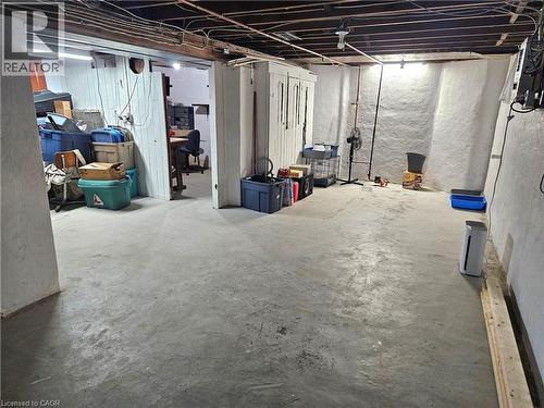 Unfinished basement featuring exposed ceiling joists, concrete flooring, painted stone walls, and a separate partially enclosed area - 75 Barons Avenue S, Hamilton, ON - Indoor Photo Showing Basement