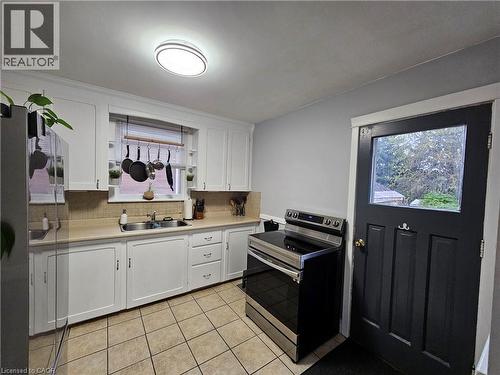 Kitchen featuring white cabinetry, a stainless steel sink, beige countertops, and tile flooring - 75 Barons Avenue S, Hamilton, ON - Indoor Photo Showing Kitchen With Double Sink