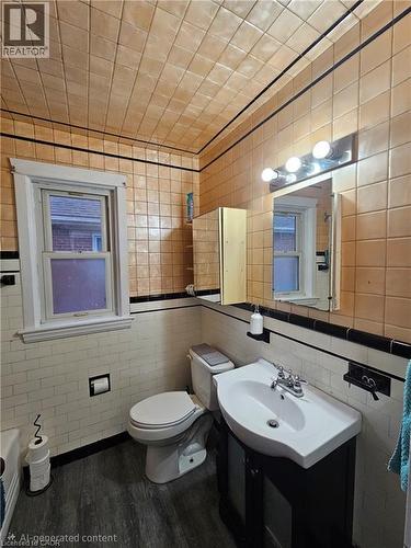 Bathroom featuring tile walls, a vanity with an integrated sink, and wood-finish flooring - 75 Barons Avenue S, Hamilton, ON - Indoor Photo Showing Bathroom
