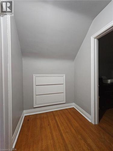 Hardwood flooring complements the neutral wall tones in this angled hallway, featuring a built-in storage unit with three drawers and white trim - 75 Barons Avenue S, Hamilton, ON - Indoor Photo Showing Other Room