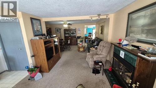 Living area featuring a fireplace with a green tiled surround, wood mantel, and hearth - 257 Cedar Street, Simcoe, ON - Indoor Photo Showing Other Room