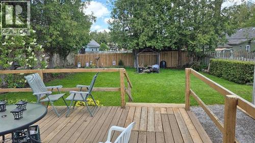 Expansive backyard featuring a wood deck, manicured lawn, and mature trees - 257 Cedar Street, Simcoe, ON - Outdoor With Deck Patio Veranda With Backyard
