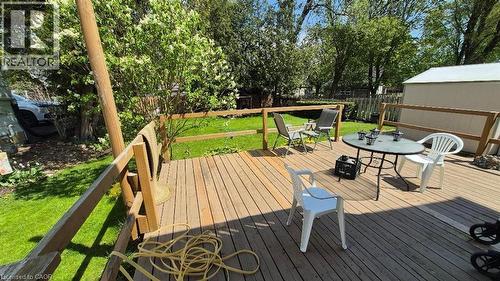 Expansive wood-plank deck with wood railing, overlooking a fenced yard featuring mature trees and a storage shed - 257 Cedar Street, Simcoe, ON - Outdoor With Deck Patio Veranda
