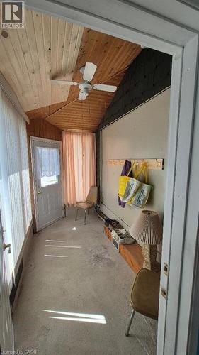 Enclosed porch featuring a sloped wood-finish plank ceiling, a ceiling fan, concrete flooring, and a white entry door with frosted glass - 257 Cedar Street, Simcoe, ON - Indoor Photo Showing Other Room